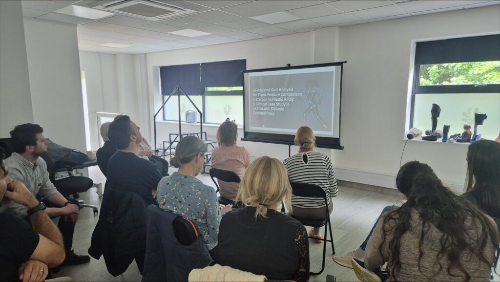 Attendees watching a presentation on AI-assisted gait analysis and orthotic comparisons during a clinical seminar